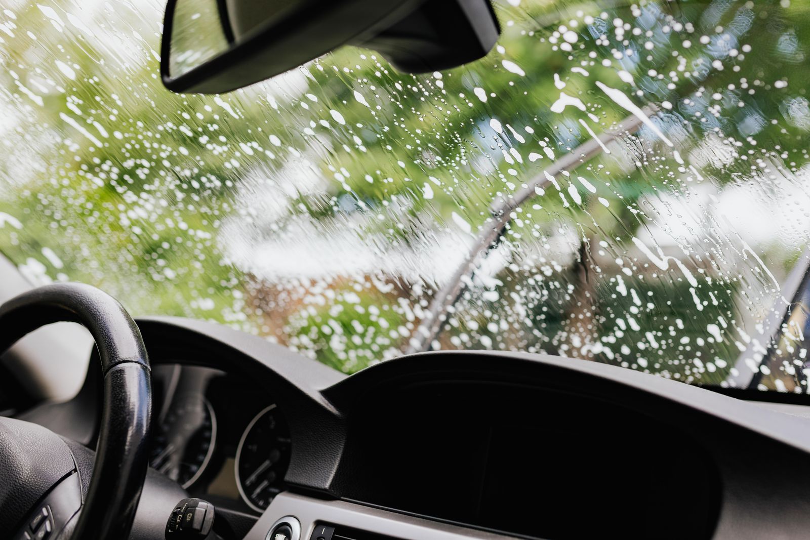 Windshield covered in wash soap seen from the driver's seat during cleaning